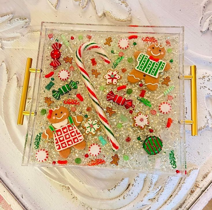 a glass tray with christmas decorations and candy canes on it, sitting on a table