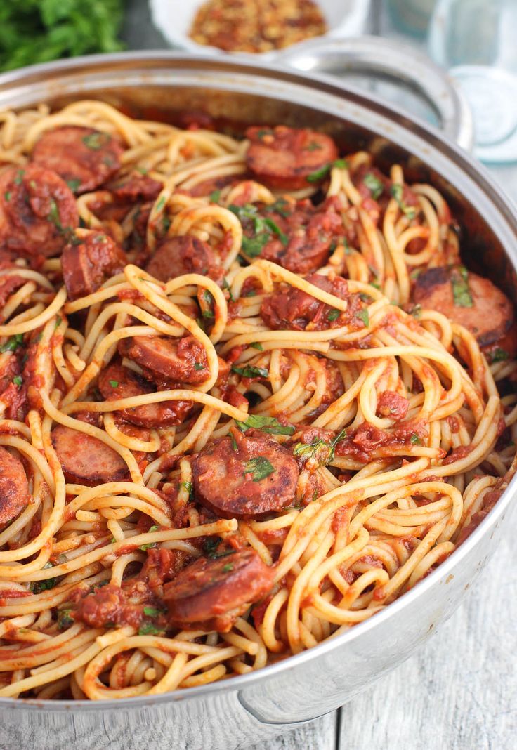 pasta with sausage and tomato sauce in a pan on a wooden table, ready to be eaten