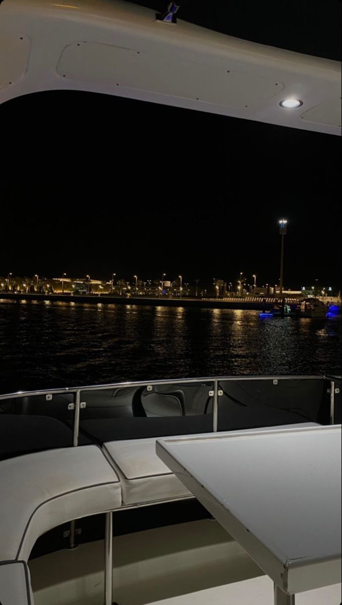 there is a table and chairs on the back of a boat in the water at night