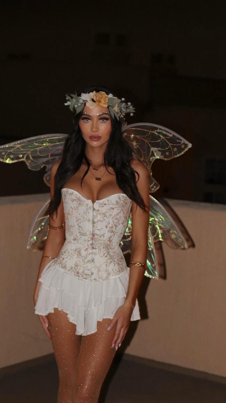 a woman in a white corset and fairy wings is posing for the camera