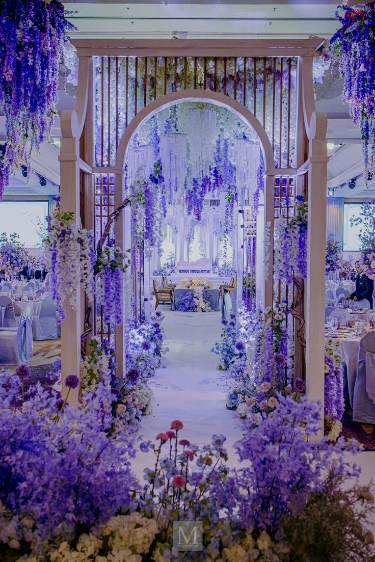 an archway decorated with purple flowers and greenery for a wedding reception at the resort