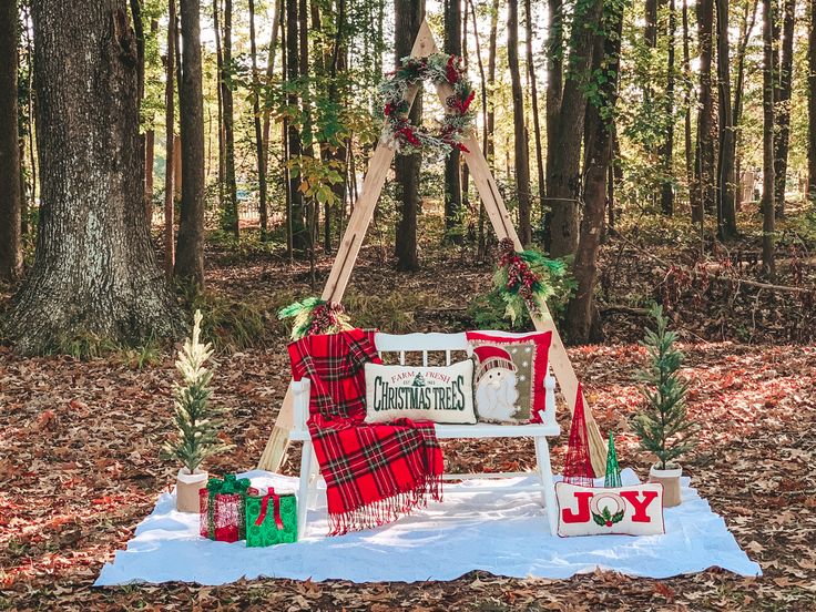 an outdoor christmas display in the woods with presents on it and decorations hanging from trees