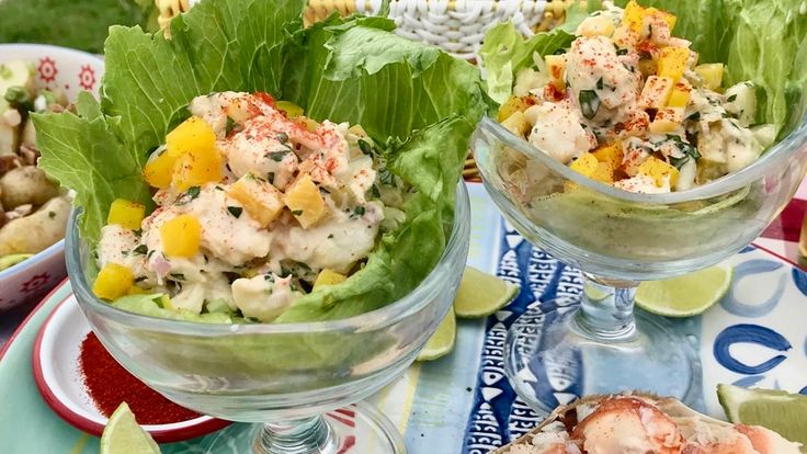 two glasses filled with food sitting on top of a blue and white table cloth next to plates