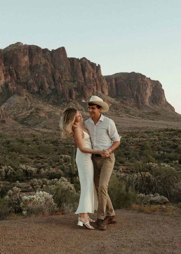 a man and woman standing next to each other in the desert