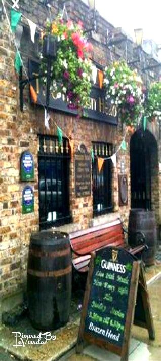 a brick building with flowers hanging from it's windows and a sign that says guinness