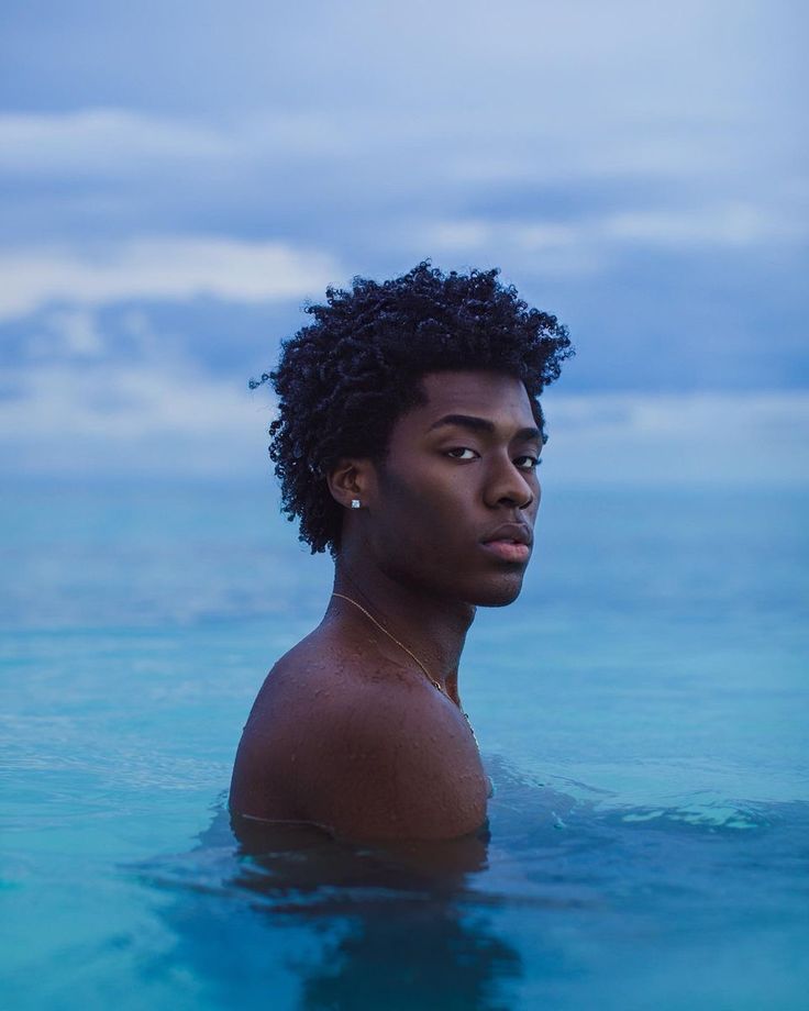 a young man is swimming in the ocean with his head turned to the side and looking off into the distance