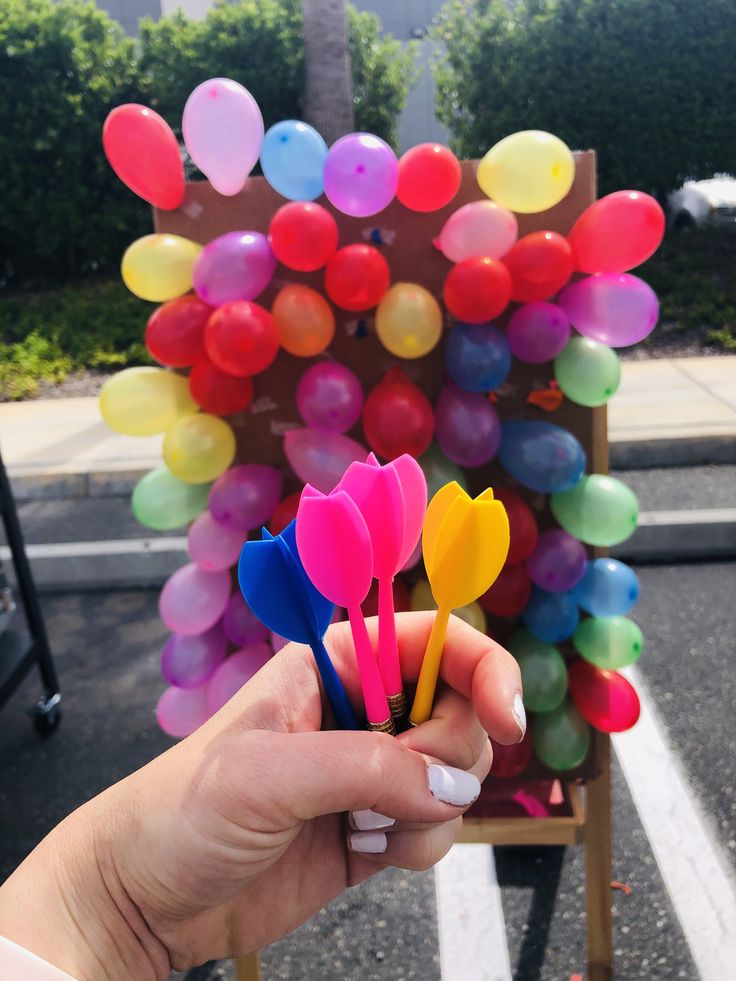 a person holding up some colorful balloons in their hand