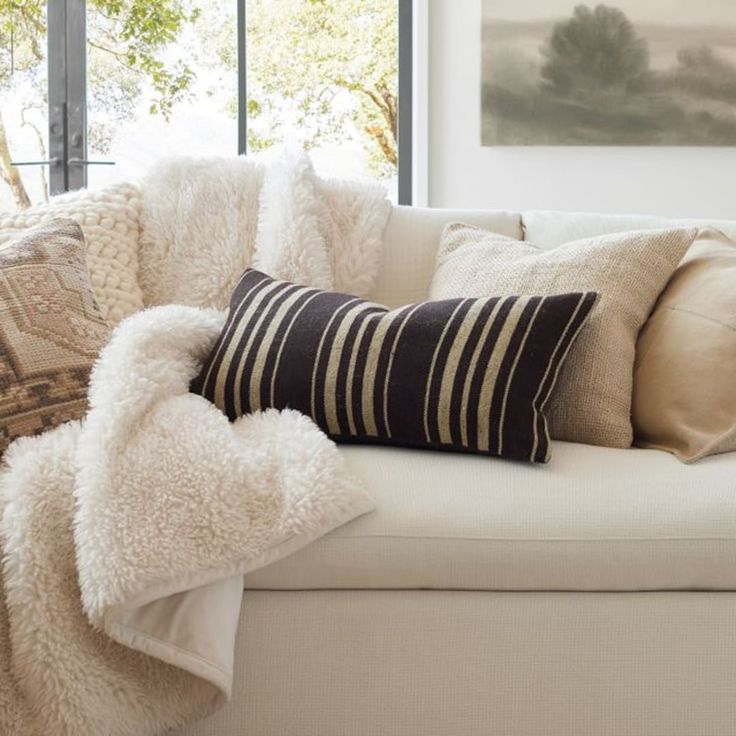 a white couch with pillows and blankets on it