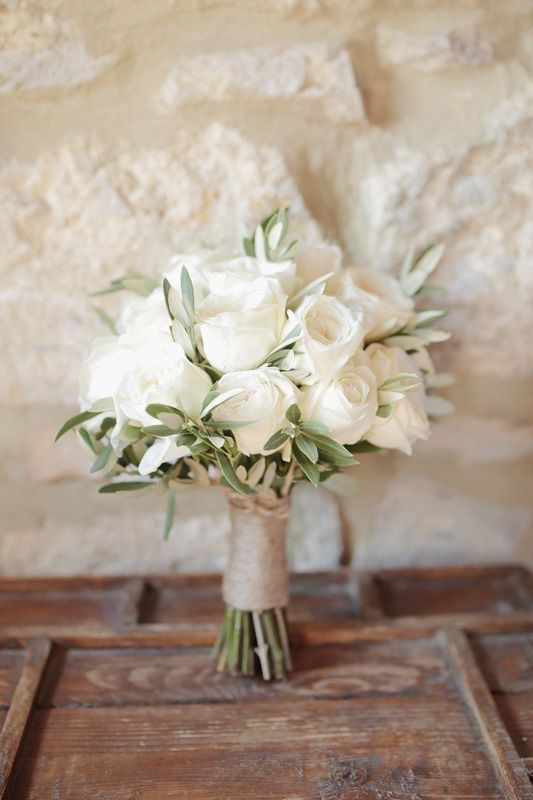 a bouquet of white flowers sitting on top of a wooden table next to a wall