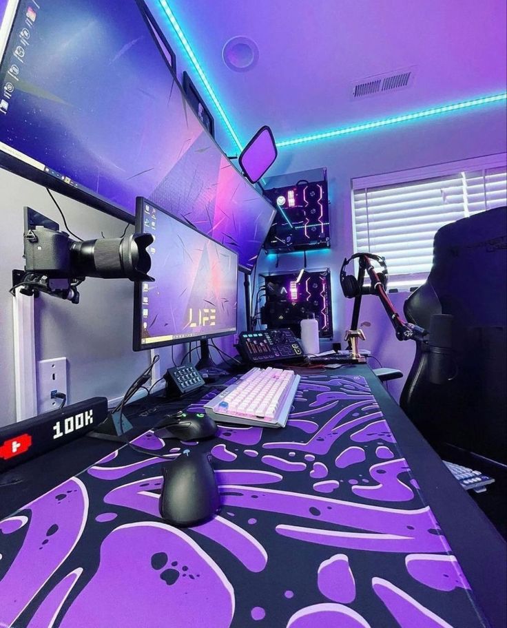 a gaming room with purple and black decorations on the desk, computer monitors and mouses