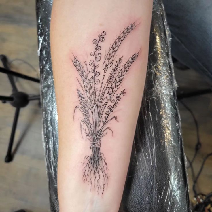 a woman's arm with a tattoo that has flowers and leaves on the side