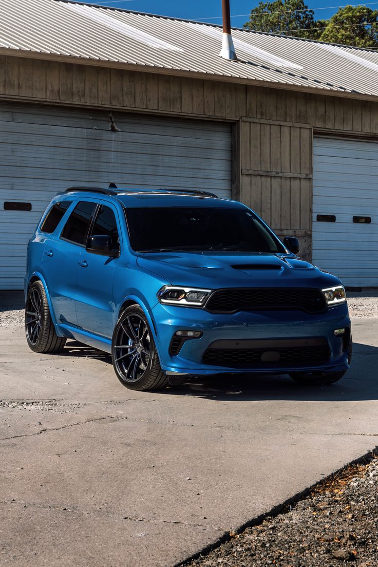 a blue dodge suv parked in front of two garage doors