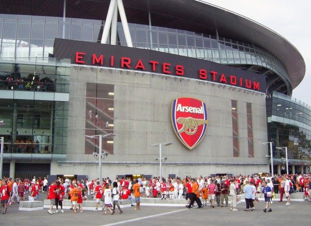 a large crowd of people standing in front of an emirates stadium entrance with fans walking around