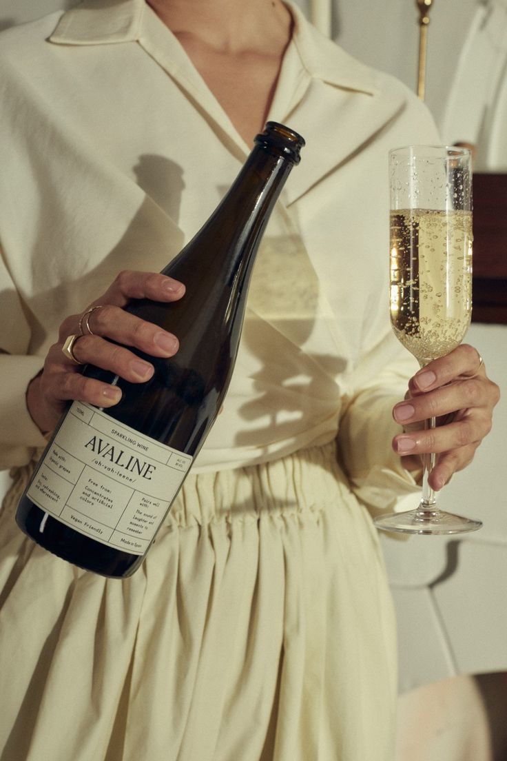 a woman holding a wine glass and bottle