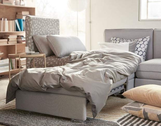 a bed sitting in the middle of a living room next to a couch and ottoman