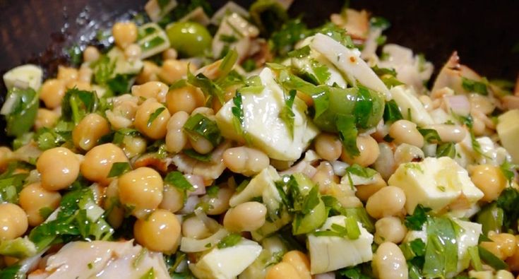 a salad with chickpeas, lettuce and other vegetables in a bowl