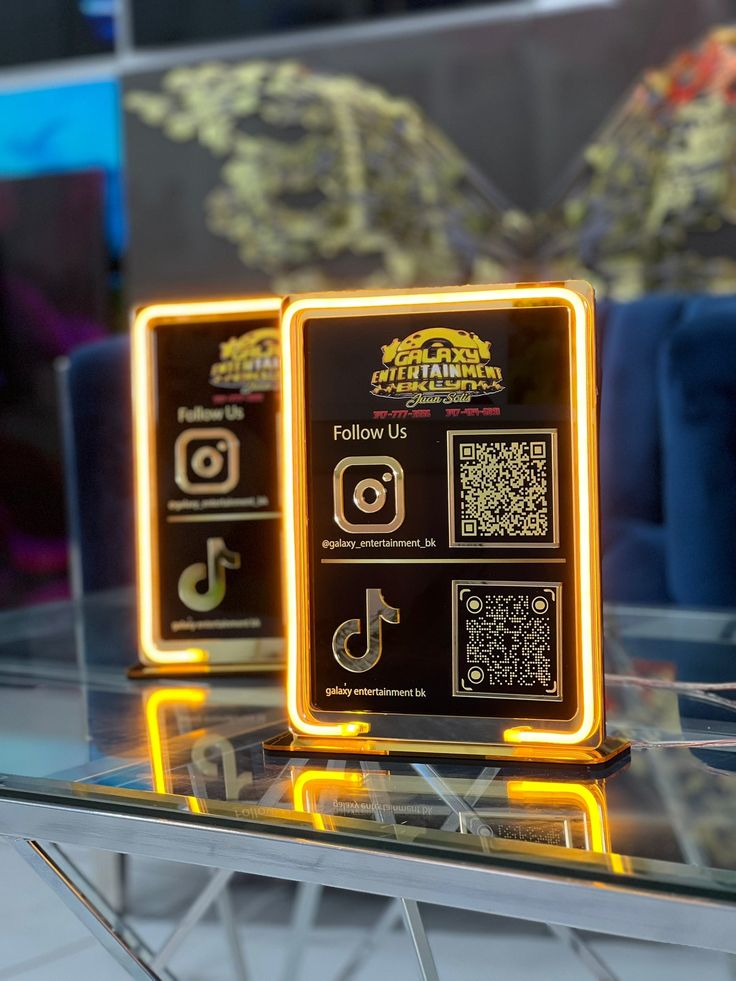 two illuminated signs sitting on top of a glass table