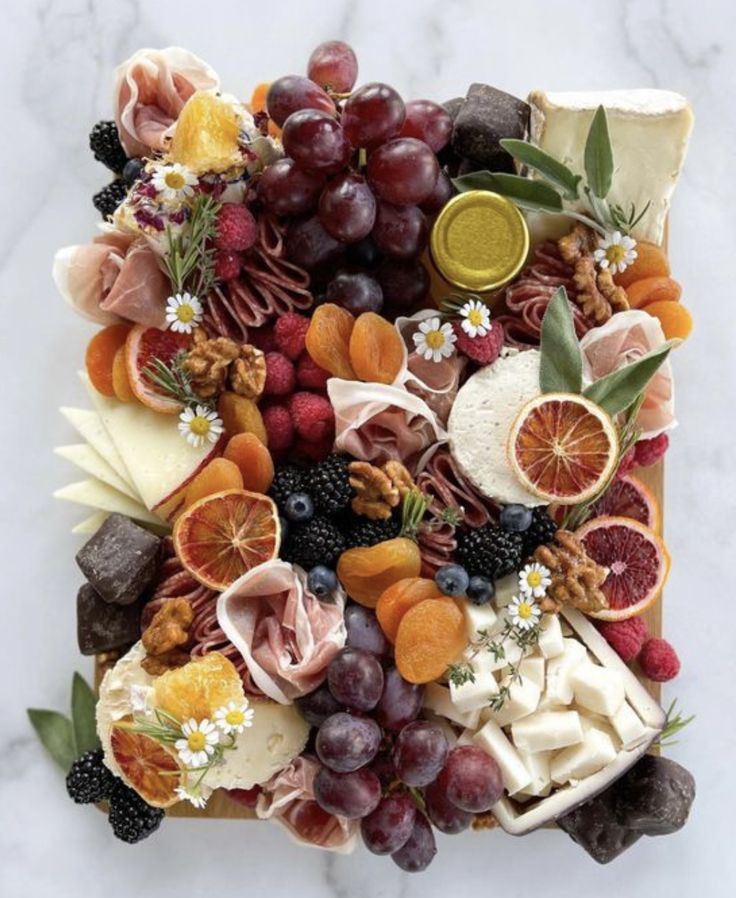 an assortment of fruits and cheeses on a marble surface