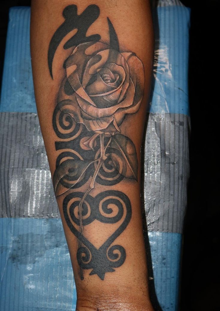 a black and white rose tattoo on the left arm with swirly lines around it