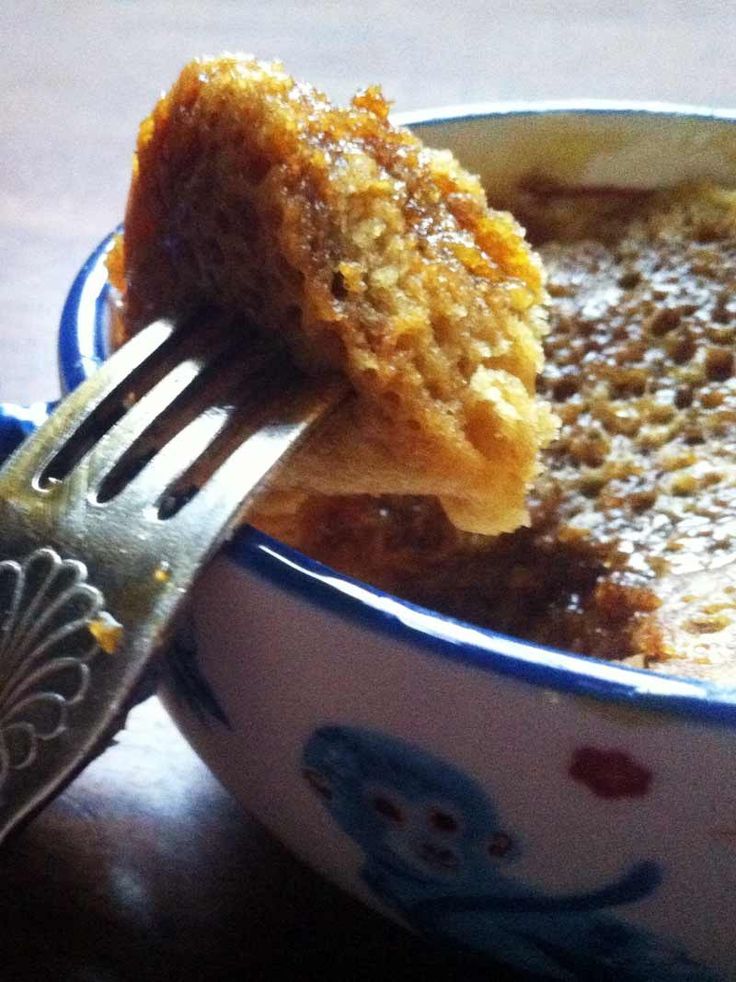 a fork with some food in it and a bowl on the table next to it