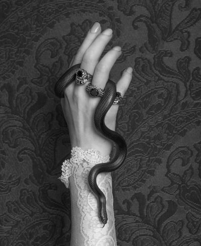 a woman's hand holding a black snake on top of her arm with white lace