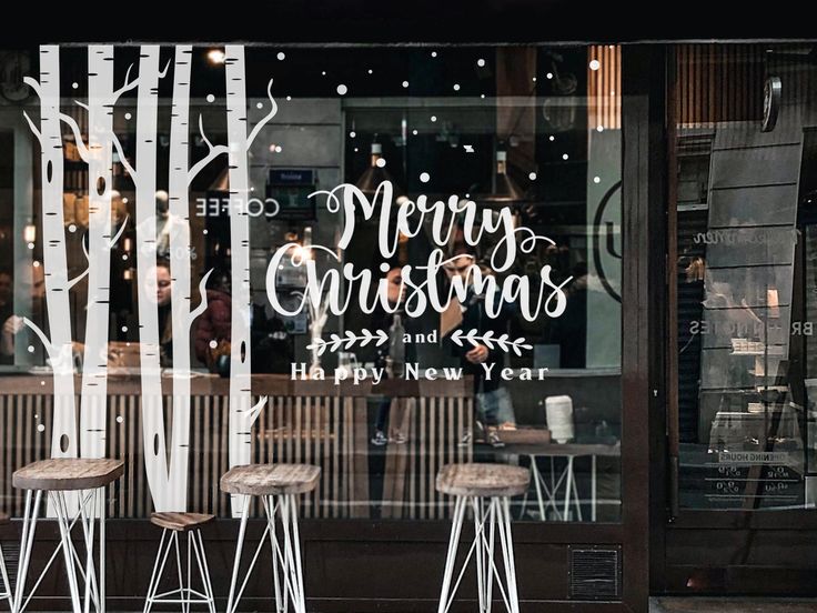 two bar stools sitting in front of a store window with christmas decorations on it