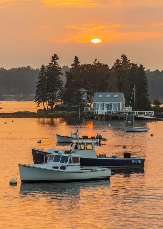 two boats floating in the water at sunset