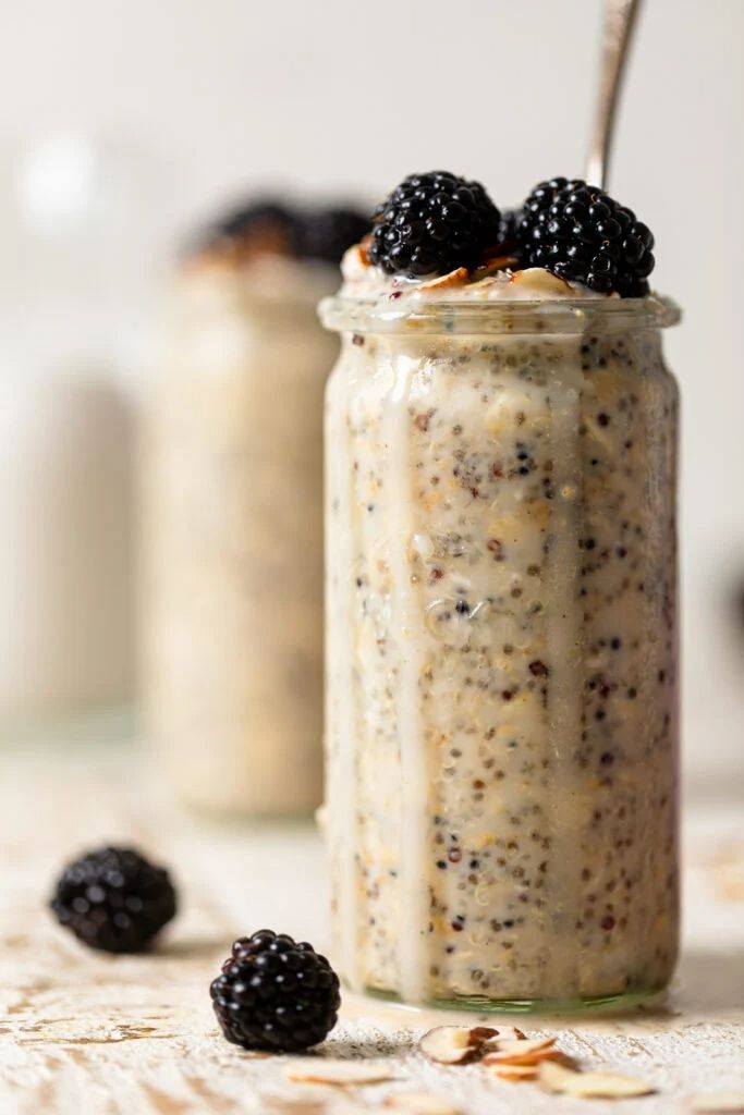 two jars filled with oatmeal and blackberries on top of a table