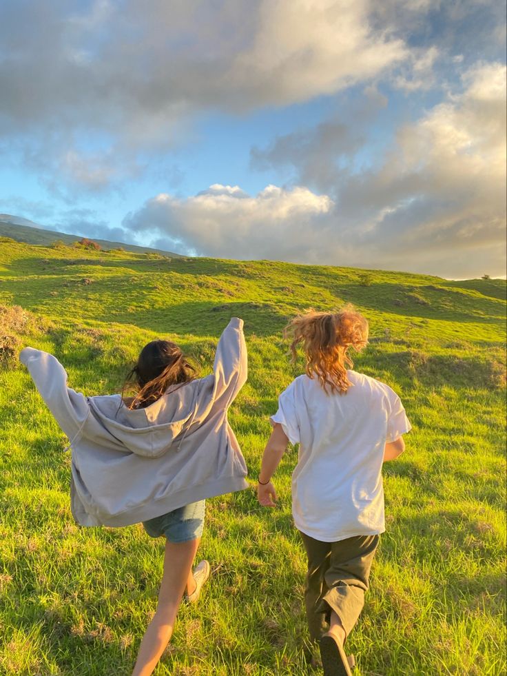 two young women running across a lush green field