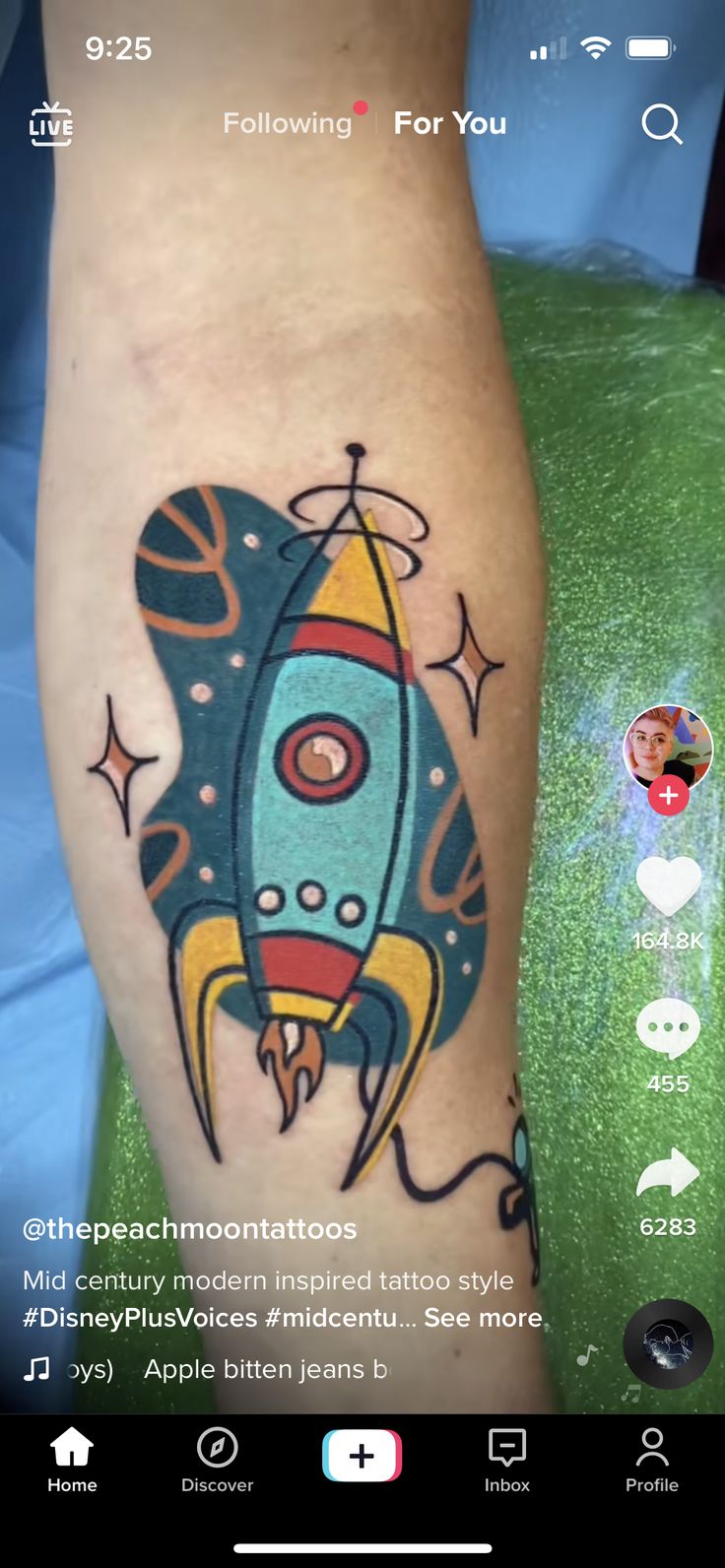 a tattoo on the leg of a person with a blue and yellow rocket ship in it