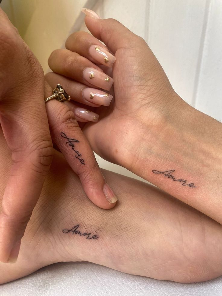 two people with matching tattoos on their feet holding one another's hand and the other finger