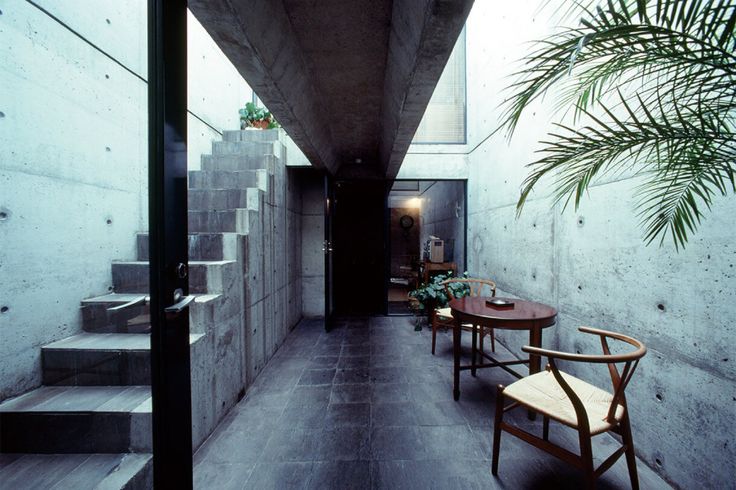 two wooden chairs sitting next to each other on top of a cement floored hallway