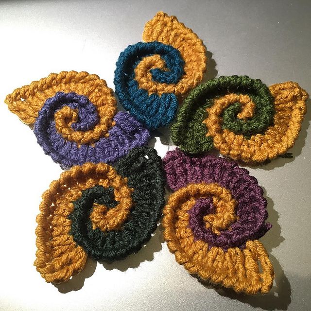 four crocheted circles are arranged in the shape of spirals on a white surface