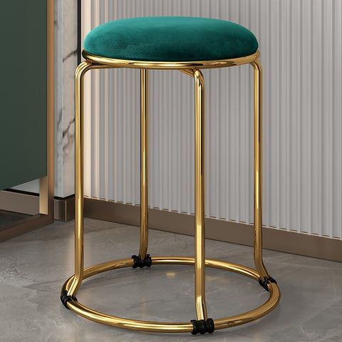 a gold stool with a green cushion on it in front of a wall and door