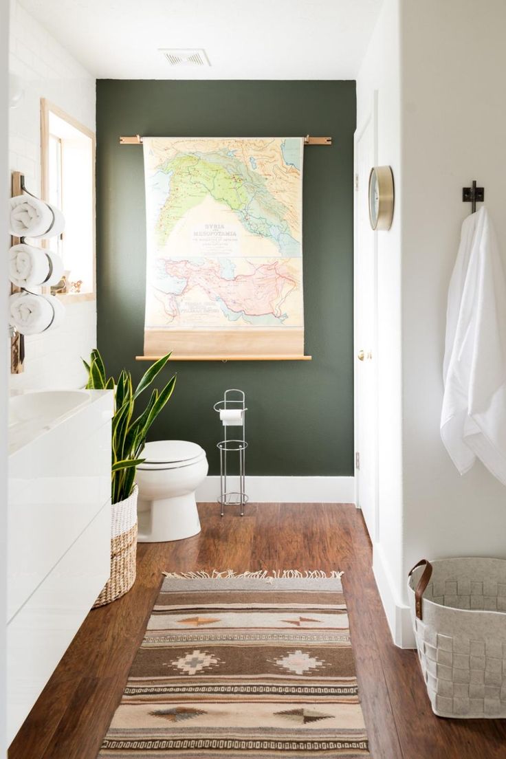 a bathroom with green walls and wood flooring in the middle, along with a map hanging on the wall