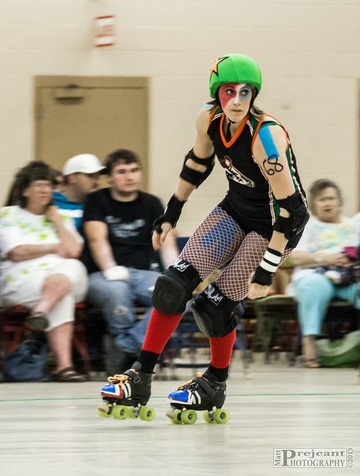 a person riding a skateboard on a court with other people sitting in the bleachers