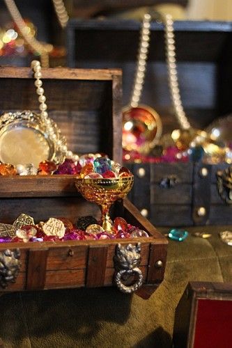 an assortment of jewelry on display in a wooden box with beads and chains hanging from it