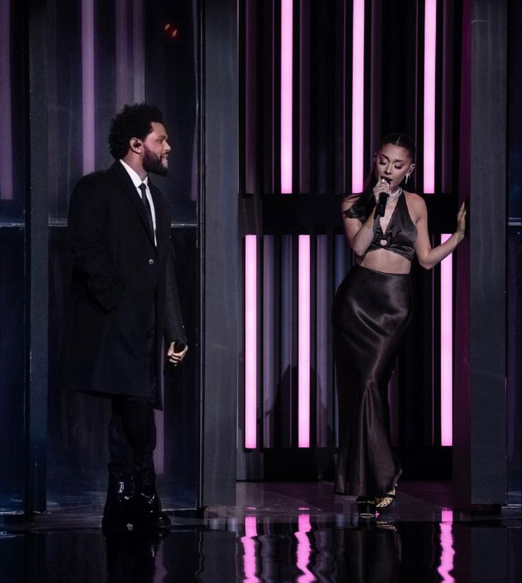 lady in black dress standing next to man on stage