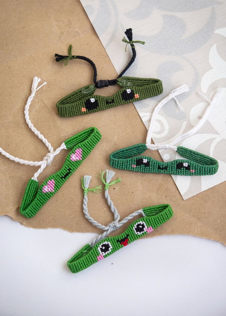 four pieces of green knitted alligators with eyes on them, tied to string