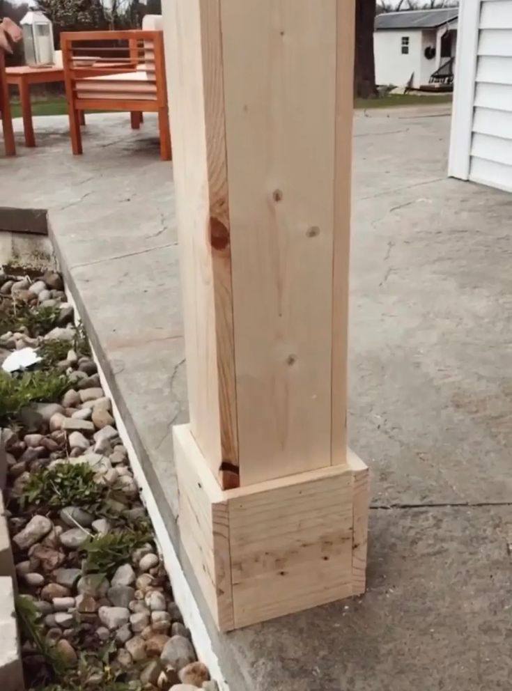 a tall wooden pole sitting on top of a cement ground next to rocks and grass