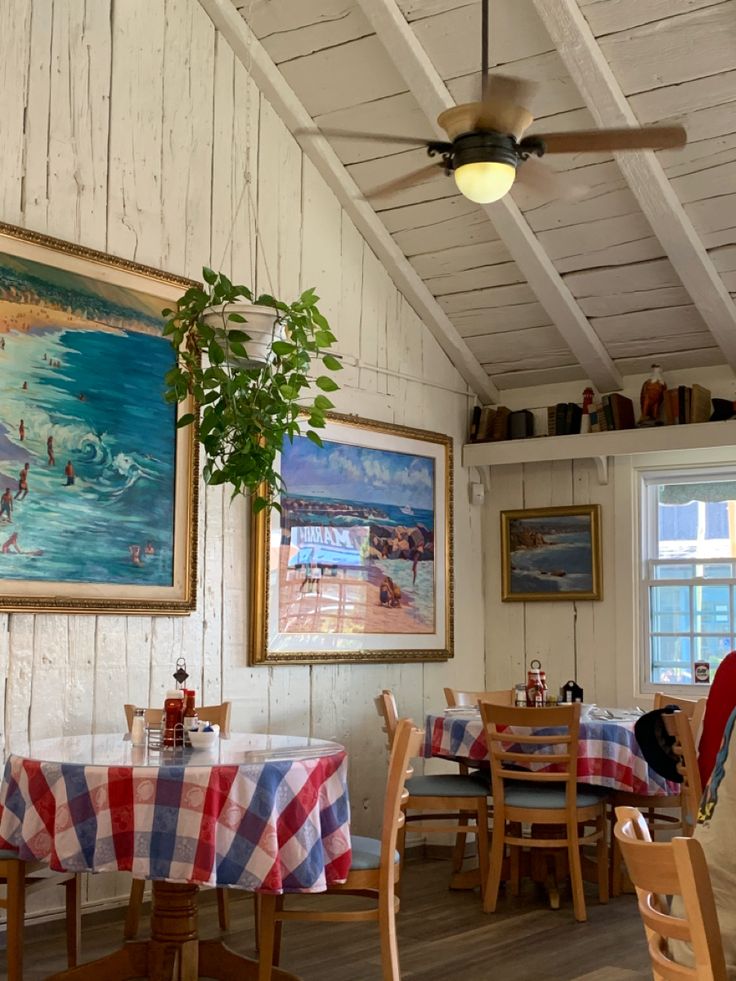 a dining room with tables and chairs covered in checkered tablecloths next to a painting on the wall