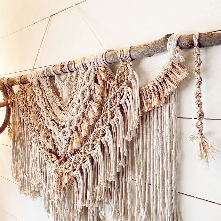 a wall hanging with tassels on it in a white walled room next to wood planks