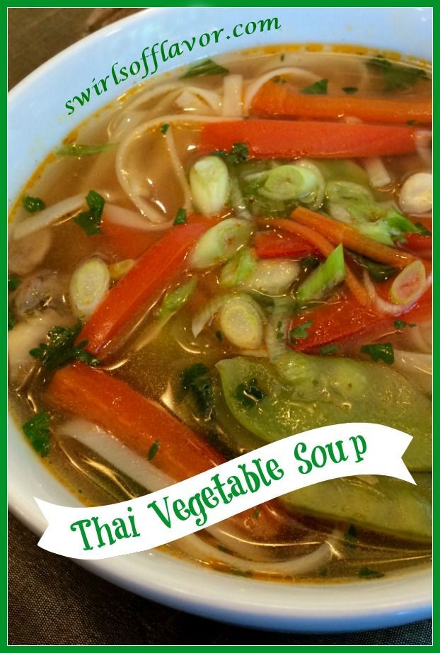 a white bowl filled with soup and vegetables on top of a wooden table next to a green border