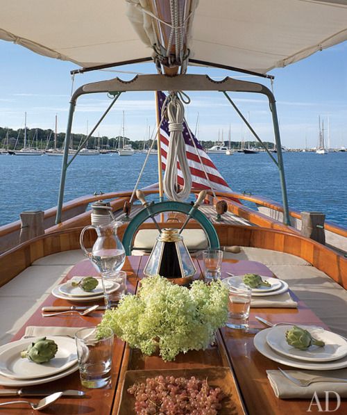 the dining table is set for two on the back of a boat with an american flag in the background