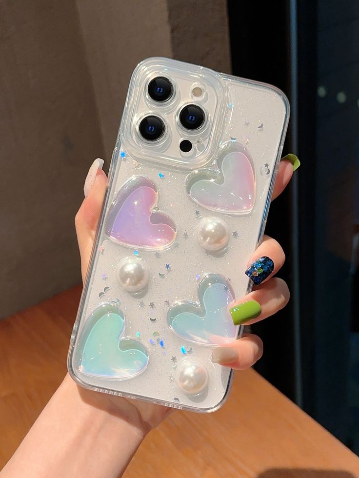 a woman's hand holding an iphone case with hearts on it