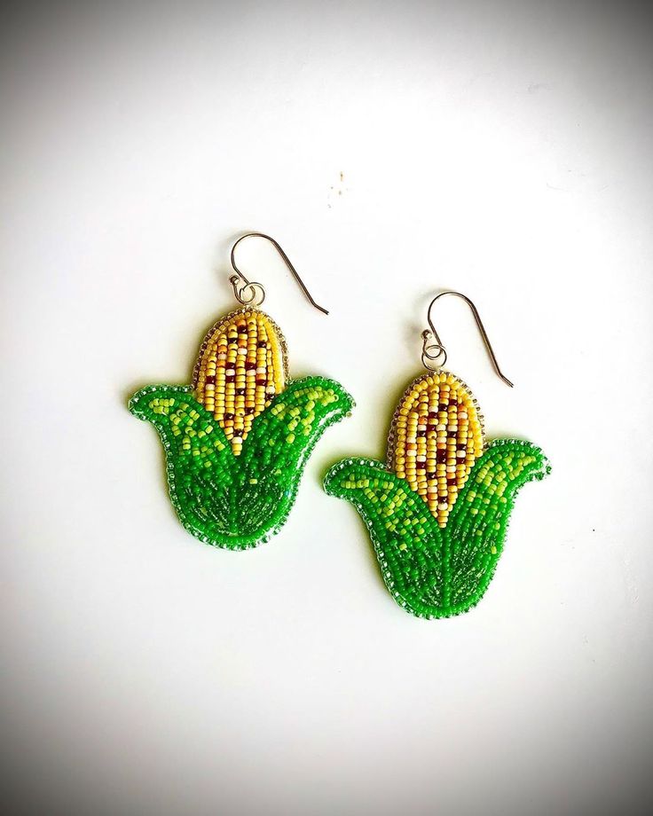 the earrings are made with seed beads and green leafy designs on them, as well as beading