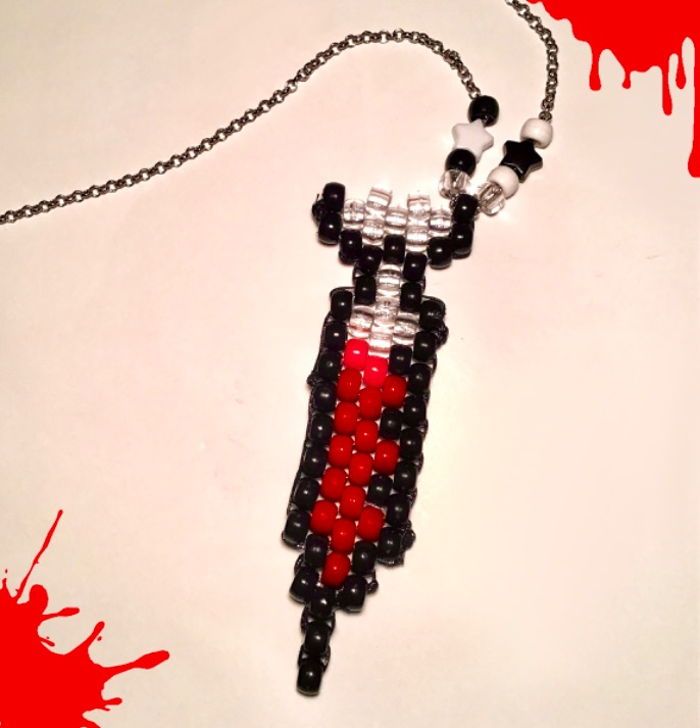 a piece of art made out of legos on a chain with blood dripping all over it