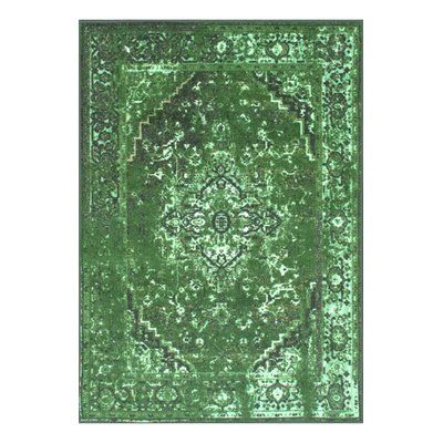 a green rug with an intricate design on the top and bottom, in front of a white background