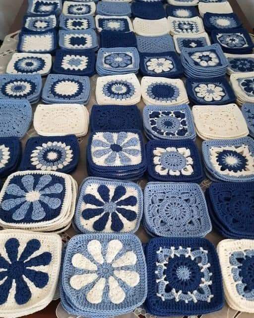 blue and white crocheted squares are arranged on a table