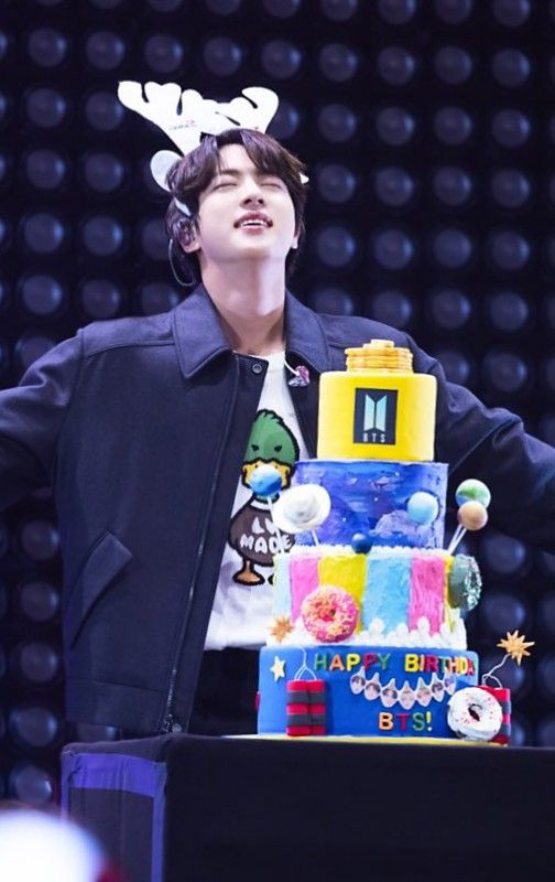 a young man standing in front of a multi - tiered cake